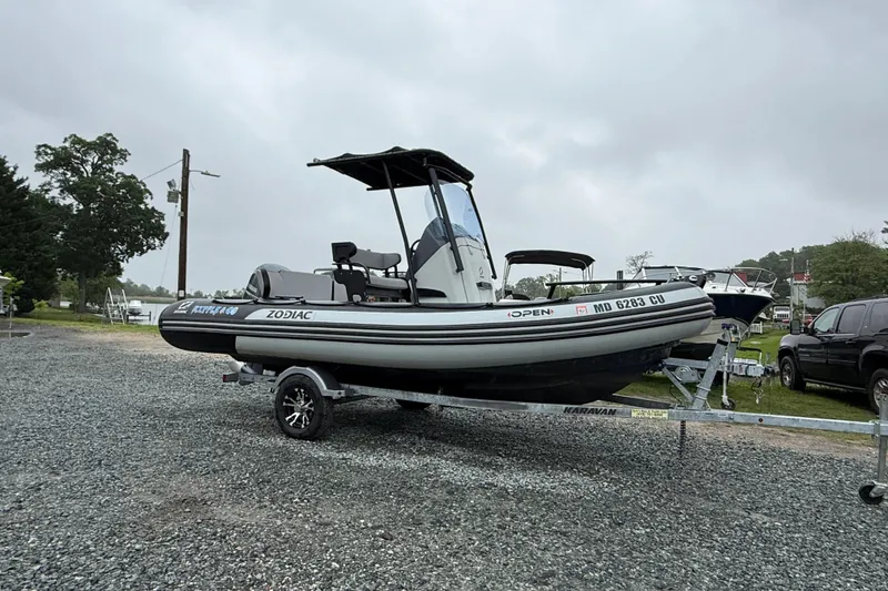 Slide: The Image of 2023 Zodiac Open 5.5 boat on trailer, parked outdoors on gravel. - 7