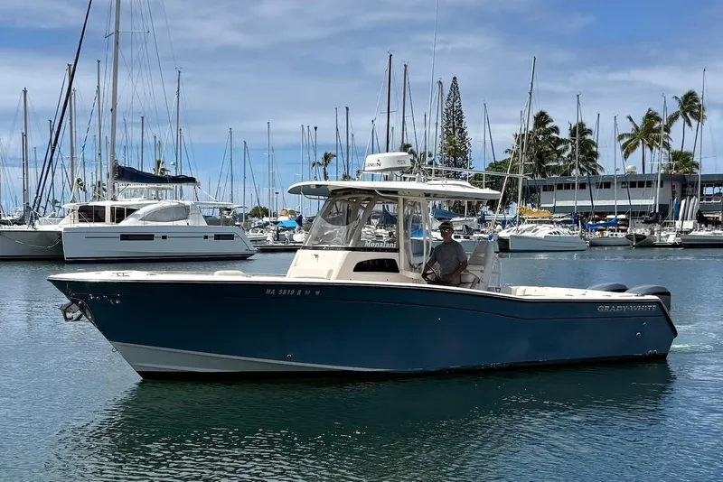 The Image of 2020 Grady-White Canyon 306 boat docked in a marina with sailboats and palm trees. - 1