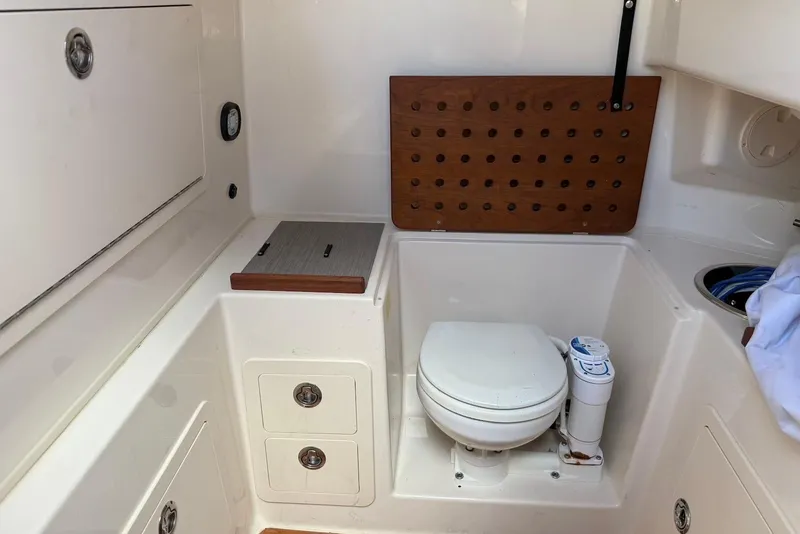 Slide: The Image of 2020 Grady-White Canyon 306 boat interior with compact marine toilet and storage compartments. - 18