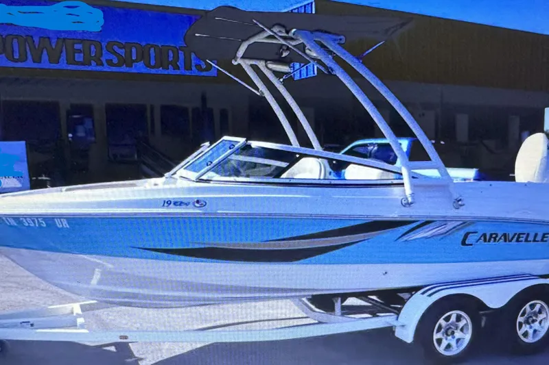 Slide: The Image of 2021 Caravelle 19 EBo Bowrider boat on trailer, parked outside Powersports store. - 14