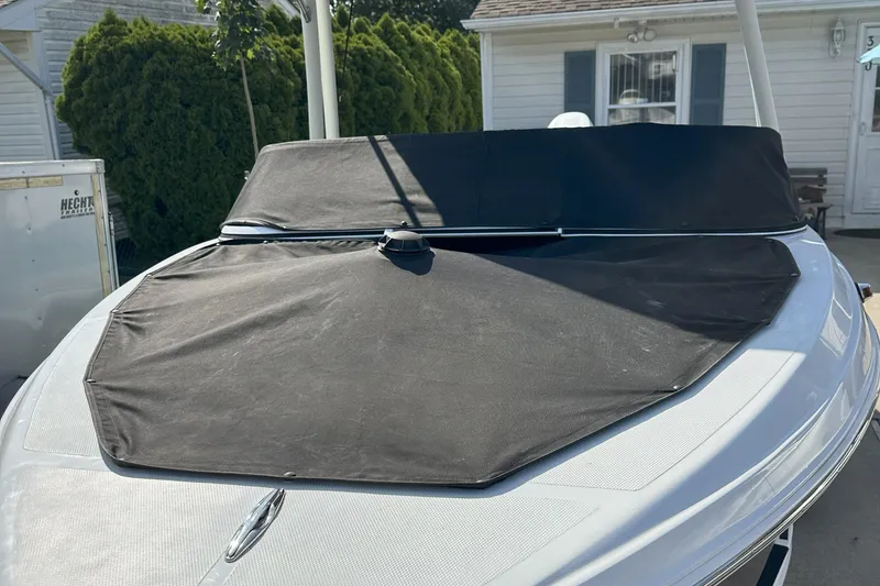 Slide: The Image of 2021 Caravelle 19 EBo Bowrider with black cover, parked near a house. - 17