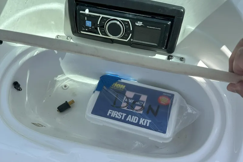 Slide: The Image of First aid kit and stereo in 2021 Caravelle 19 EBo Bowrider boat compartment. - 21