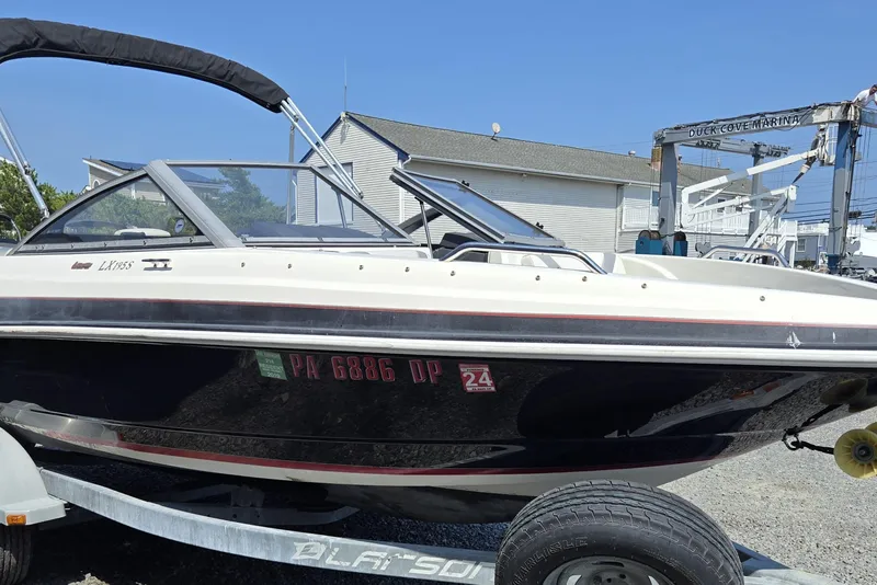 Slide: The Image of 2014 Larson LX 195S IO boat on trailer at marina, sunny day. - 10