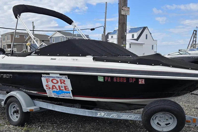 Slide: The Image of 2014 Larson LX 195S IO boat for sale, covered and on a trailer, in a residential area. - 14