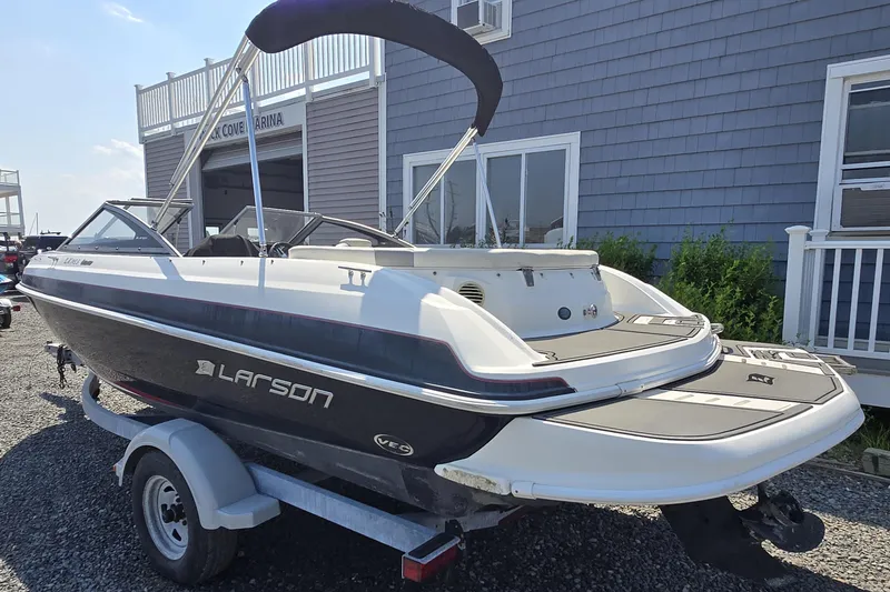 Slide: The Image of 2014 Larson LX 195S IO boat on trailer near marina building. - 4