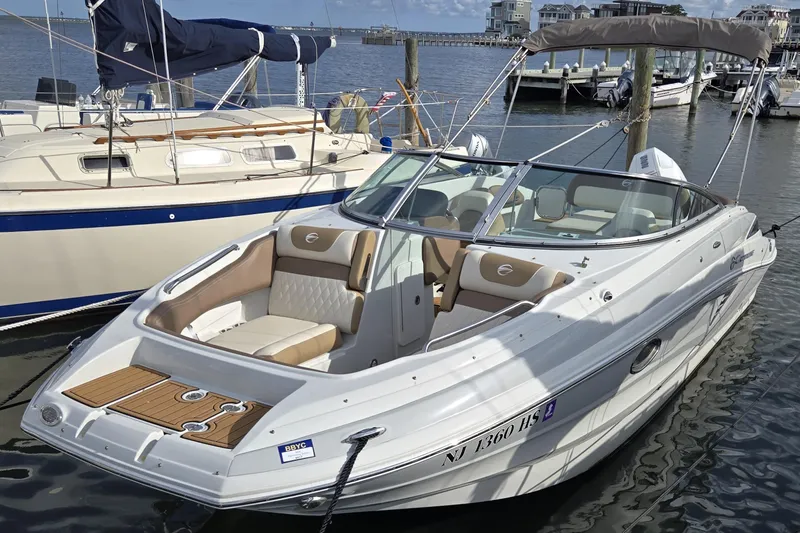Slide: The Image of 2023 Crownline Eclipse E235 XS boat docked in marina, featuring sleek design and spacious seating. - 2