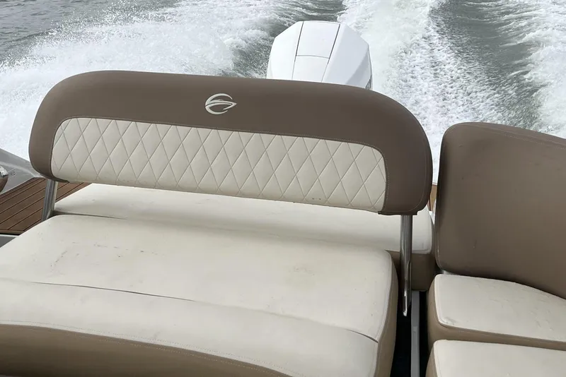 Slide: The Image of 2023 Crownline Eclipse E235 XS boat interior with cushioned seating and water wake. - 9