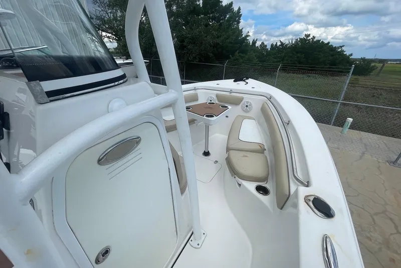Slide: The Image of 2016 Sea Pro 219 Center Console boat interior with seating and table, under cloudy sky. - 6