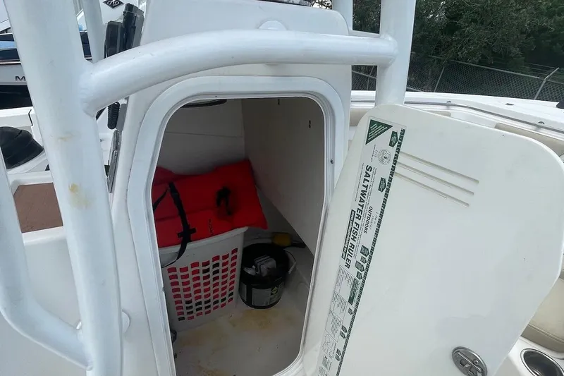 Slide: The Image of 2016 Sea Pro 219 Center Console storage compartment with life jacket and fishing gear. - 9