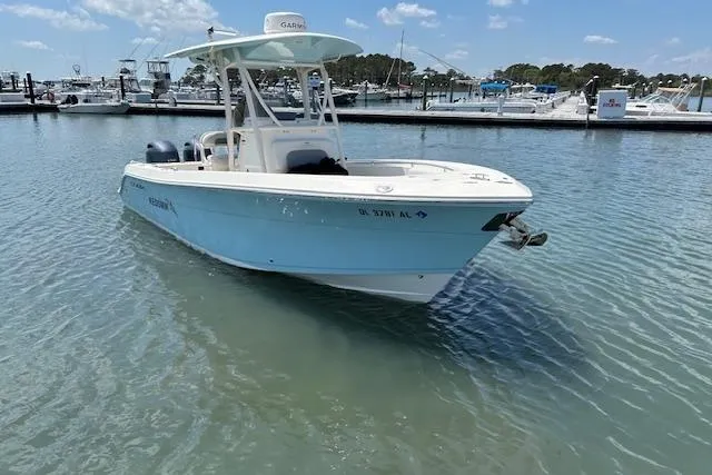 Slide: The Image of 2018 Cobia 237 Center Console boat docked in a marina under clear skies. - 0
