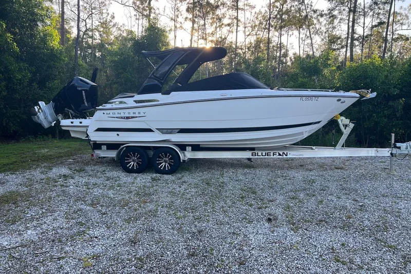 Slide: The Image of 2025 Monterey 255 Super Sport boat on trailer, parked outdoors with trees in background. - 1