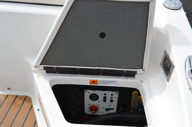 Slide: The Image of 2018 Chaparral 250 Suncoast boat compartment with control panel and warning label. - 18