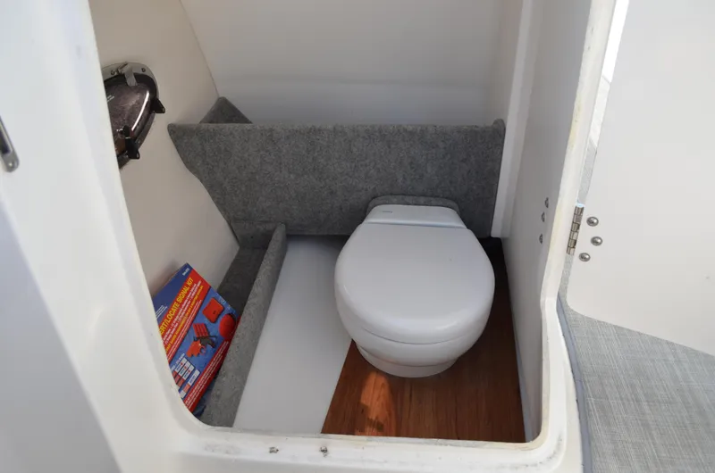 Slide: The Image of 2018 Chaparral 250 Suncoast boat interior with compact toilet and storage area. - 33
