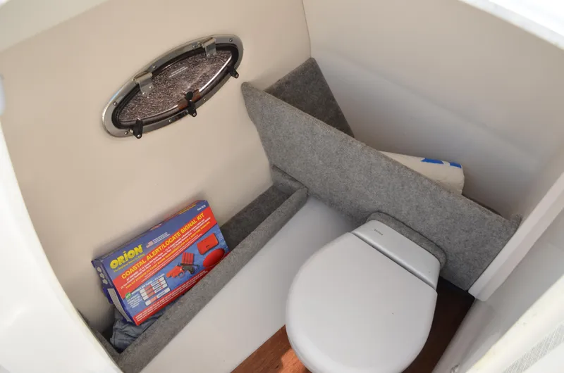 Slide: The Image of 2018 Chaparral 250 Suncoast boat interior with toilet and emergency signal kit. - 34