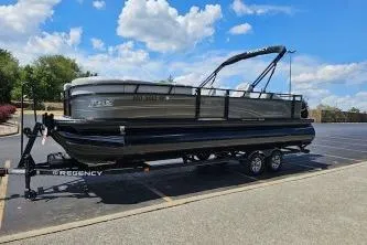 Slide: The Image of 2024 Regency 250 DL3 pontoon boat on trailer in parking lot under blue sky. - 5