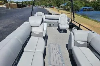 Slide: The Image of 2024 Regency 250 DL3 pontoon boat with spacious seating and modern design by the water. - 6