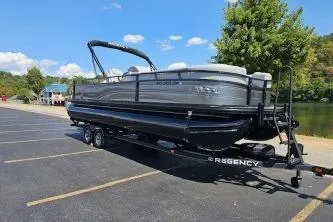 Slide: The Image of 2024 Regency 250 DL3 pontoon boat on trailer in parking lot, sunny day. - 7
