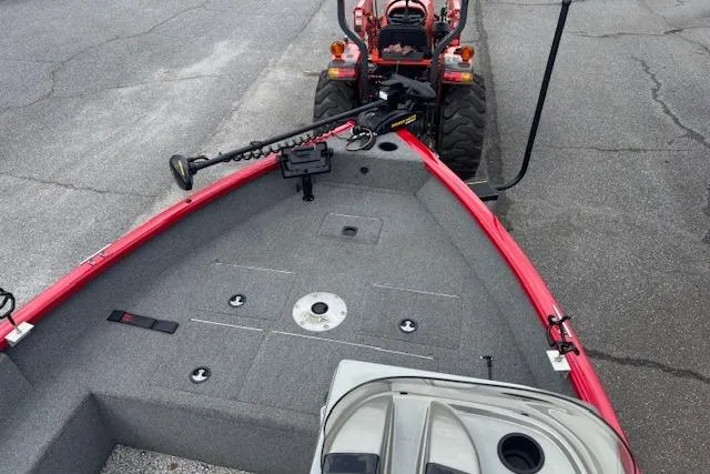 Slide: The Image of 2016 Tracker Pro Guide V-16 SC boat with red trim, parked on pavement. - 9