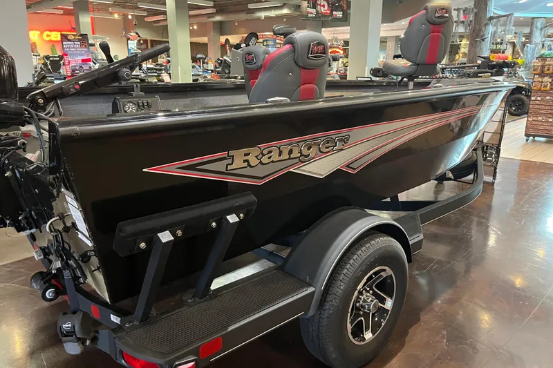 Slide: The Image of 2024 Ranger VS1665T boat in showroom, black exterior, red accents, on trailer. - 2
