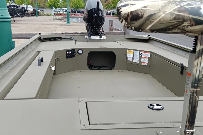 Slide: The Image of 2026 Tracker Grizzly 1654 T Sportsman boat interior with motor, storage, and camouflage seat. - 2