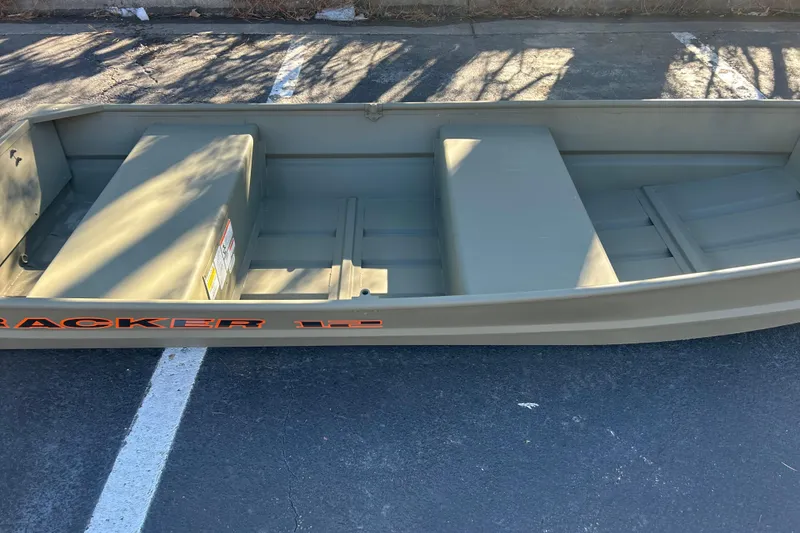 Slide: The Image of 2026 Tracker Grizzly 12 Jon boat on pavement, showcasing interior seating and storage. - 2