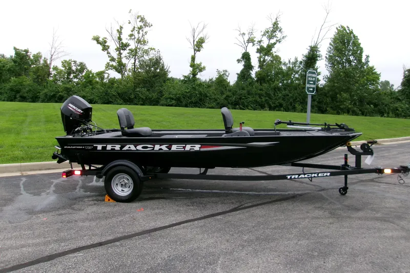 The Image of 2025 Tracker Panfish 17 boat on trailer, parked on asphalt near green grass. - 0