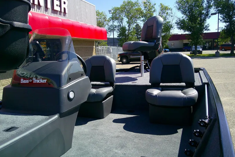 Slide: The Image of 2026 Tracker Bass Tracker Classic XL boat interior with seating and console, parked outdoors. - 2