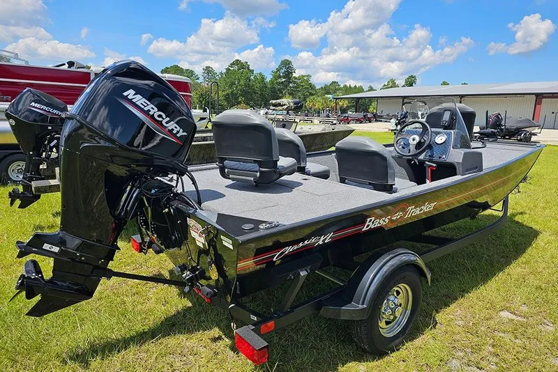 Slide: The Image of 2026 Tracker Bass Tracker Classic XL boat with Mercury engine on grassy field. - 7