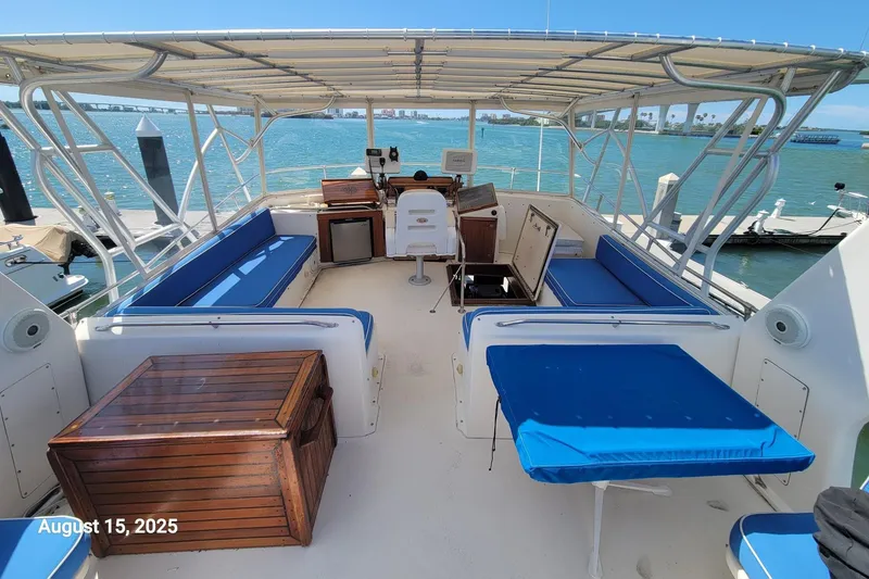 Slide: The Image of 1985 Chris-Craft 500 Constellation yacht deck with blue seating, docked by the ocean. - 4