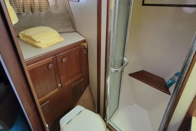 Slide: The Image of 1985 Chris-Craft 500 Constellation bathroom with shower, wooden cabinets, and yellow towels. - 40
