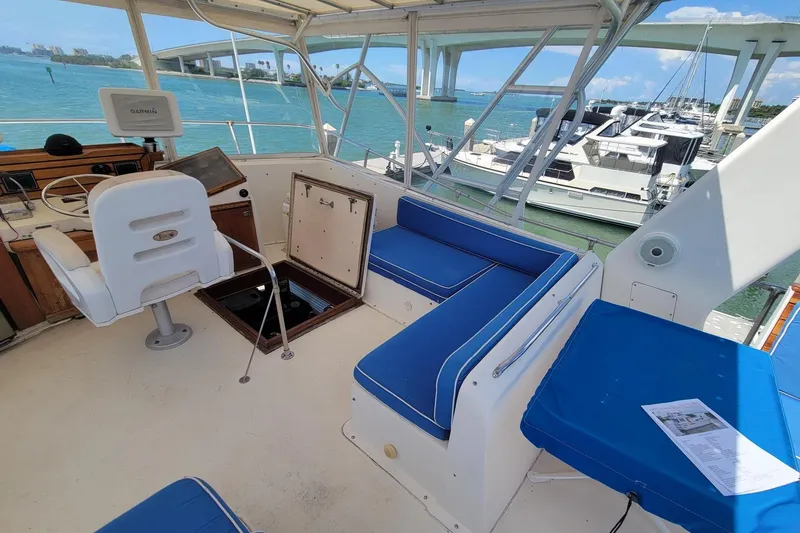 Slide: The Image of 1985 Chris-Craft 500 Constellation yacht interior with blue seating and helm, docked by marina. - 9