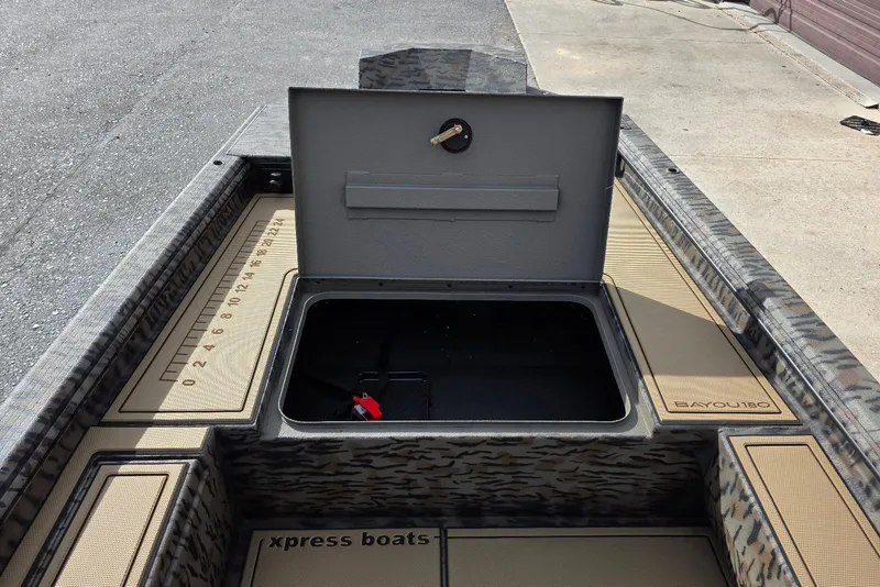 Slide: The Image of 2026 Xpress Bayou 180 boat with open storage compartment and measuring ruler. - 12