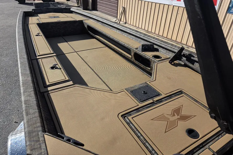 Slide: The Image of 2026 Xpress Bayou 180 boat interior with tan deck and storage compartments. - 25