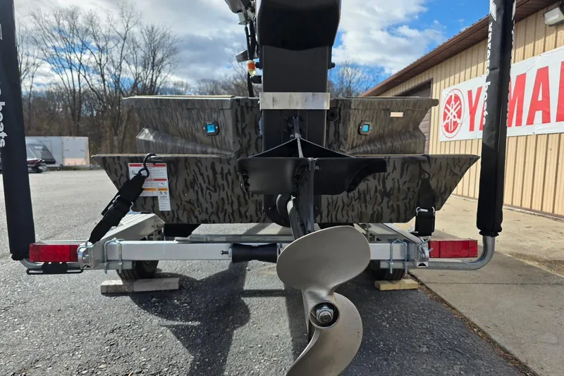 Slide: The Image of Rear view of 2026 Xpress Bayou 180 boat on trailer, showcasing propeller and camo design. - 7