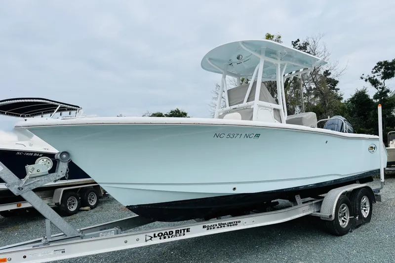 Slide: The Image of 2024 Sea Hunt Ultra 229 boat on trailer, side view with trees in background. - 2