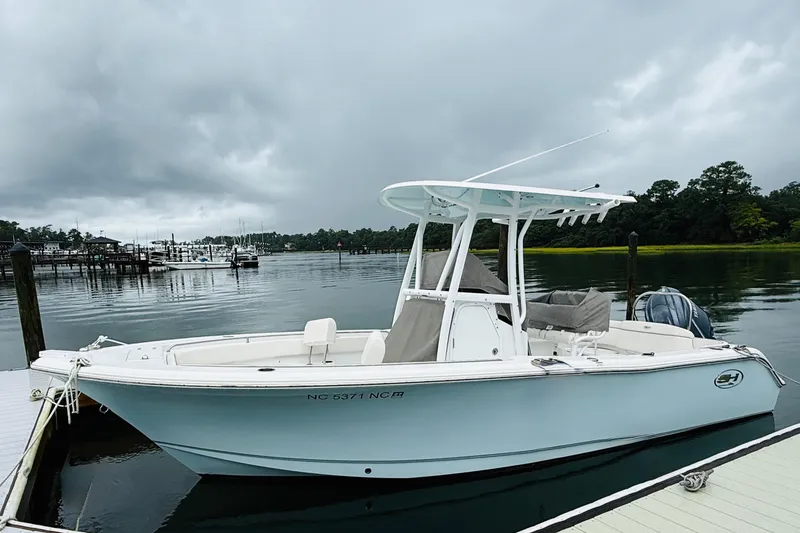 Slide: The Image of 2024 Sea Hunt Ultra 229 boat docked on a calm, overcast day. - 3