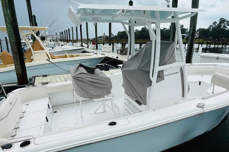 Slide: The Image of 2024 Sea Hunt Ultra 229 boat docked, featuring covered seats and a sleek design. - 8
