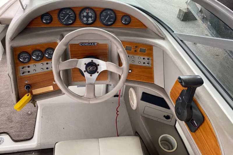 Slide: The Image of 1999 Cobalt 252 boat dashboard with steering wheel, gauges, and wood panel accents. - 5