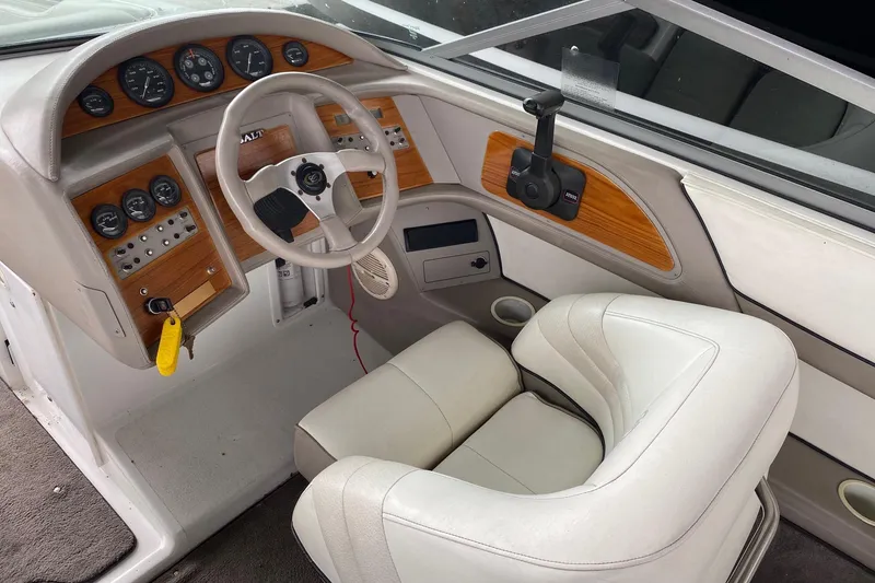 Slide: The Image of 1999 Cobalt 252 boat interior with steering wheel, gauges, and beige seating. - 6