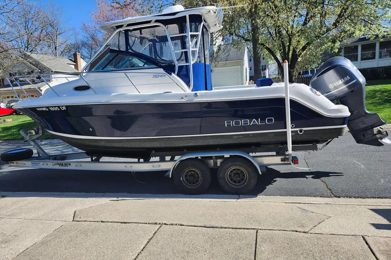 Slide: The Image of 2015 Robalo R245 Walkaround boat on trailer, parked in residential area. - 4