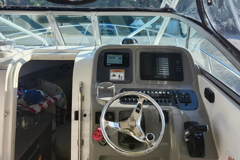 Slide: The Image of 2015 Robalo R245 Walkaround boat cockpit with steering wheel and navigation controls. - 9