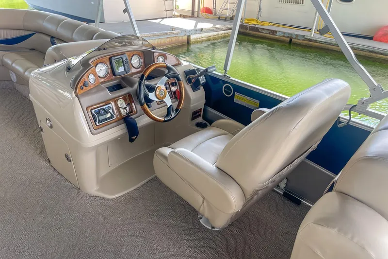 Slide: The Image of Interior of a 2011 Berkshire 263 SLX boat with beige seating and a wooden dashboard. - 12