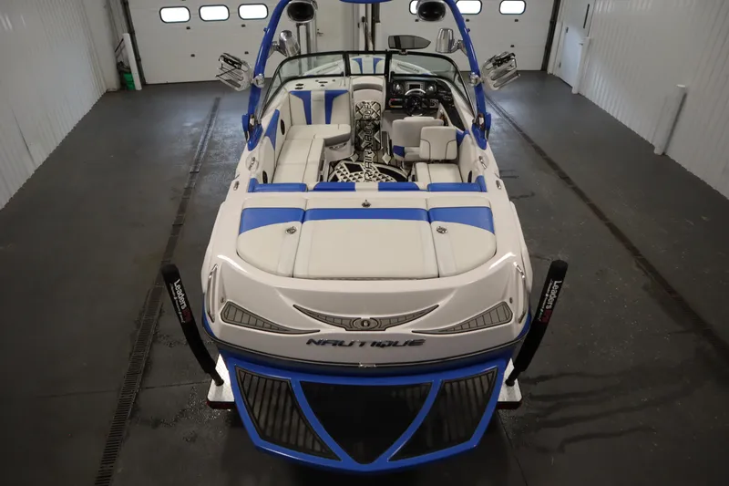 Slide: The Image of 2011 Nautique 210 SUPER AIR boat with blue and white interior in a garage setting. - 10