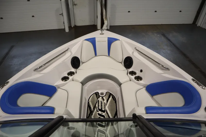 Slide: The Image of 2011 Nautique 210 SUPER AIR boat interior with blue and white seating, cup holders, and speakers. - 11