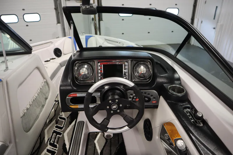 Slide: The Image of 2011 Nautique 210 SUPER AIR boat dashboard with steering wheel and control panel in a garage. - 18
