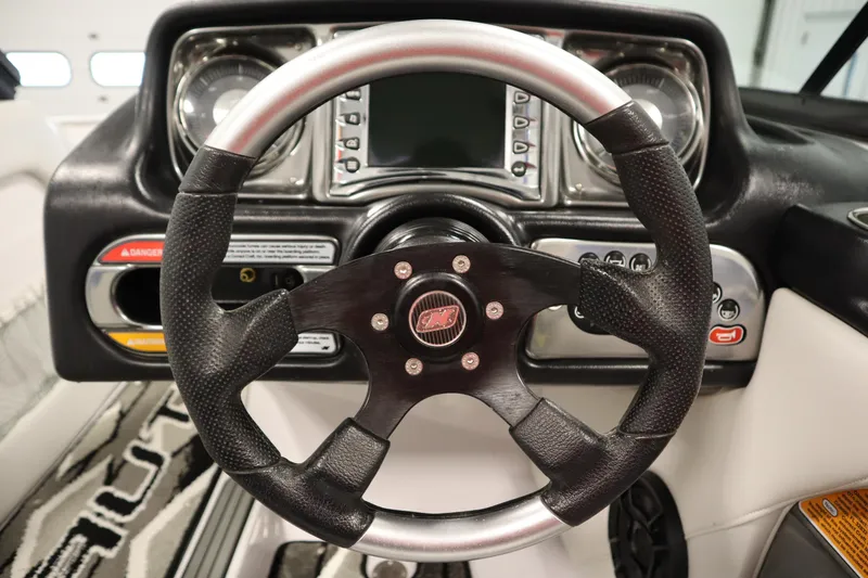 Slide: The Image of Steering wheel and dashboard of 2011 Nautique 210 SUPER AIR boat, featuring modern controls. - 19