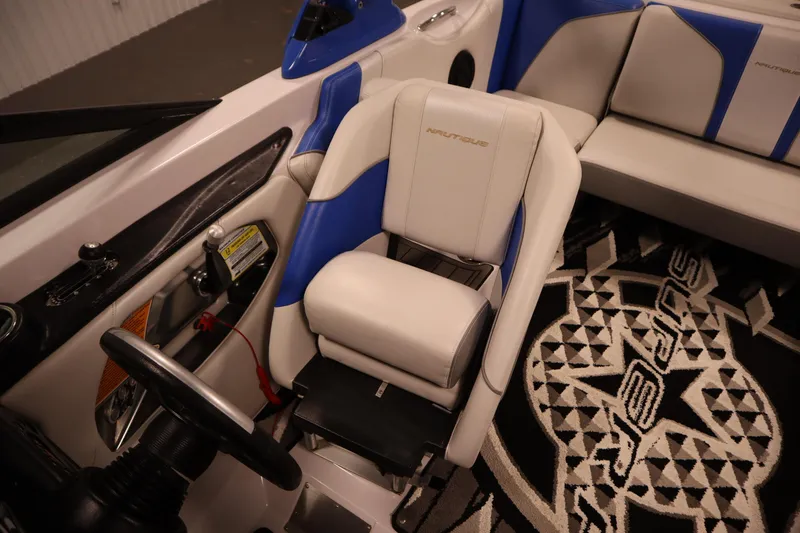Slide: The Image of 2011 Nautique 210 SUPER AIR boat interior with blue and white seating and steering wheel. - 27