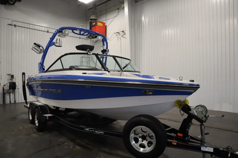 Slide: The Image of 2011 Nautique 210 SUPER AIR boat in a garage, blue and white design. - 3