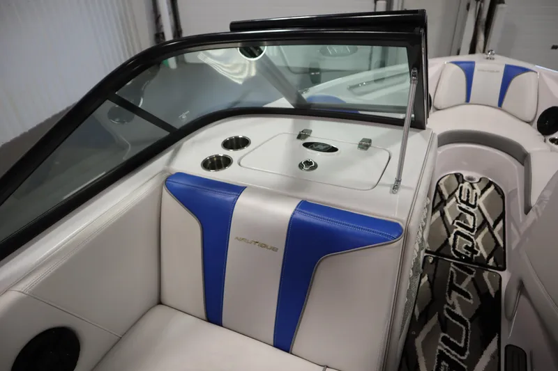 Slide: The Image of 2011 Nautique 210 SUPER AIR boat interior with blue and white seating, cup holders, and logo. - 30
