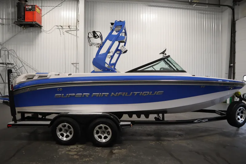 Slide: The Image of 2011 Nautique 210 SUPER AIR boat in a garage, blue and white design. - 4